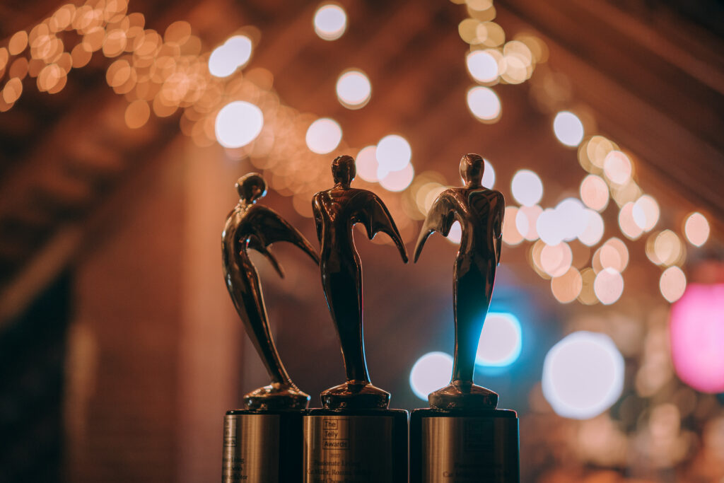 Three Telly Awards trophies with a blurred background of warm string lights